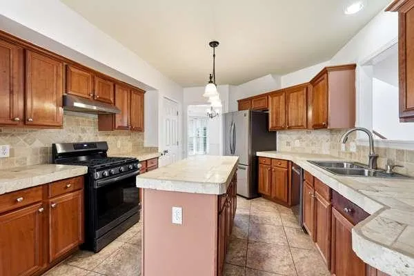 a kitchen with stainless steel appliances granite countertop a sink stove cabinets granite counter tops and a window