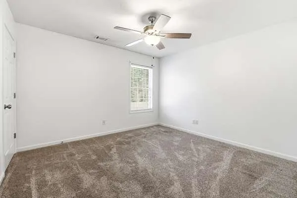an empty room with windows and fan