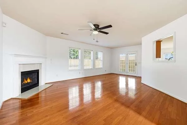 a view of an empty room with wooden floor fireplace and a window