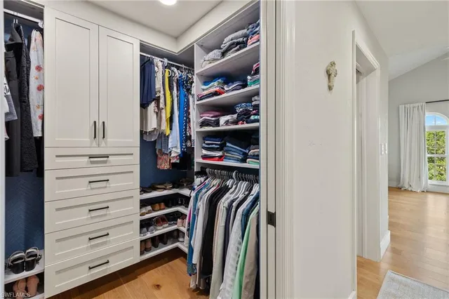 a view of walk in closet with clothes and shoes