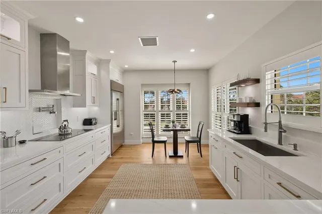 a large white kitchen with lots of counter space and windows