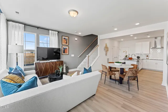 a living room with furniture kitchen view and a wooden floor