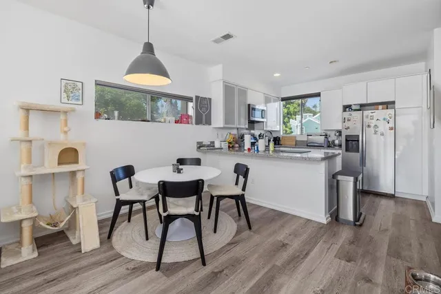 a kitchen with stainless steel appliances a dining table chairs stove and refrigerator
