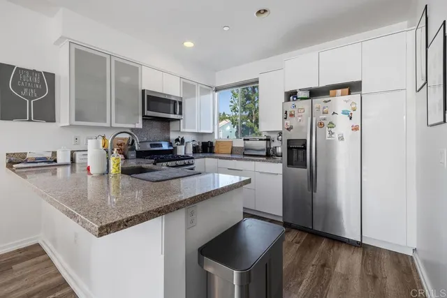 a kitchen with stainless steel appliances a sink a stove a refrigerator and cabinets