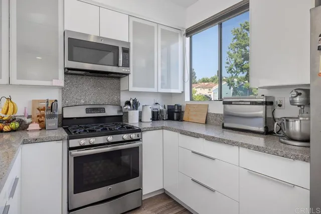 a kitchen with cabinets stainless steel appliances a sink a stove and a window