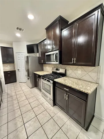 a kitchen with stainless steel appliances granite countertop a stove a sink and a microwave
