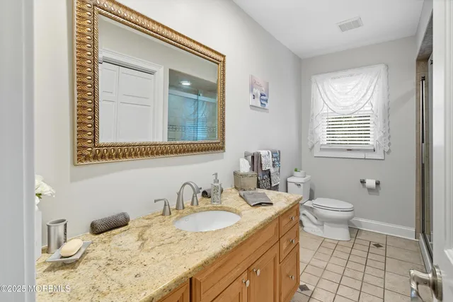 a bathroom with a granite countertop sink toilet and mirror