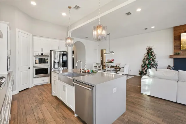 a large white kitchen with lots of counter space a sink and stainless steel appliances