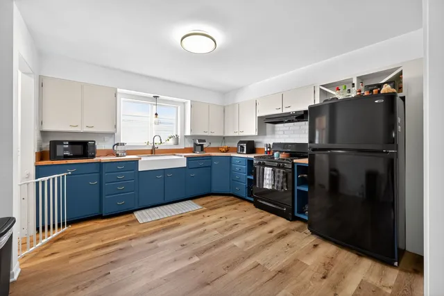 a kitchen with stainless steel appliances granite countertop a refrigerator stove top oven and a sink with wooden floors