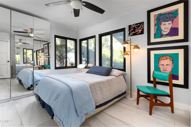 a bedroom with a bed a painting on the wall and a large window