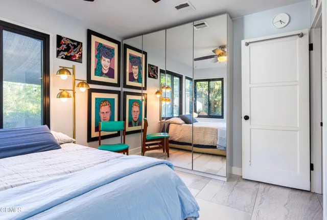 a bedroom with a bed painting on wall and a large window