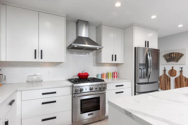 a kitchen with stainless steel appliances a stove refrigerator and cabinets