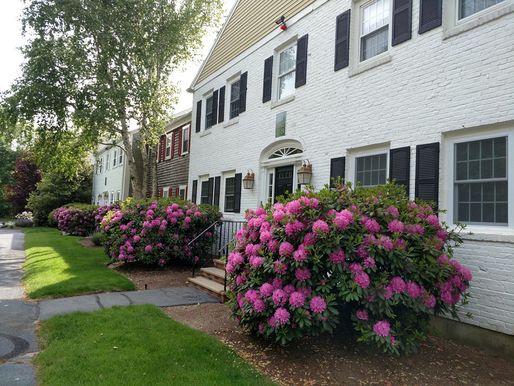 683 Old Post Road, Unit 18 Dennis, MA 02638 - Photo 2 of 25 a front view of a house with a yard and fountain in middle