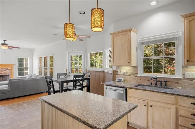 a kitchen with a sink dishwasher a dining table and chairs with wooden floor