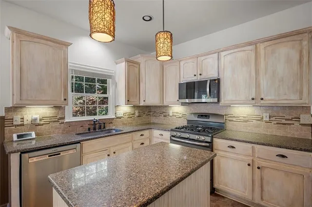 a kitchen with stainless steel appliances granite countertop a sink a stove microwave and cabinets