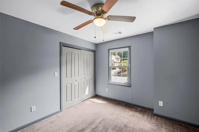 an empty room with closet and a ceiling fan