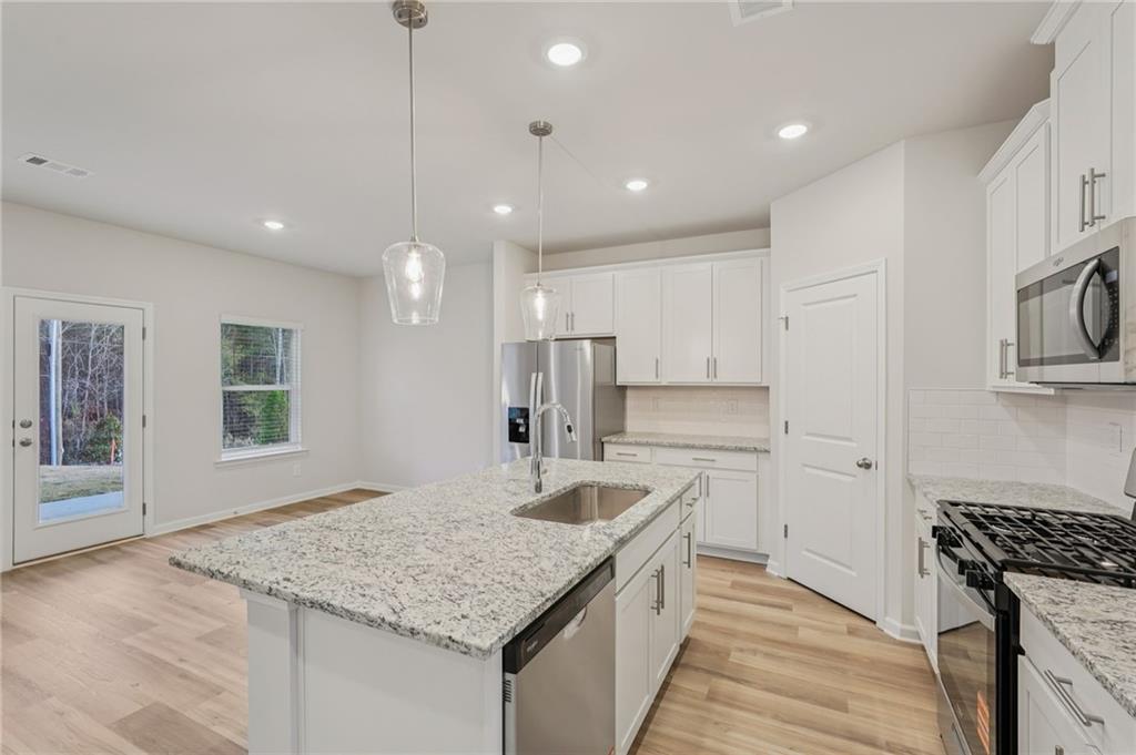 7204 Ensemble Court Fairburn, GA 30213 - Photo 13 of 56 a kitchen with stainless steel appliances granite countertop a sink stove and refrigerator