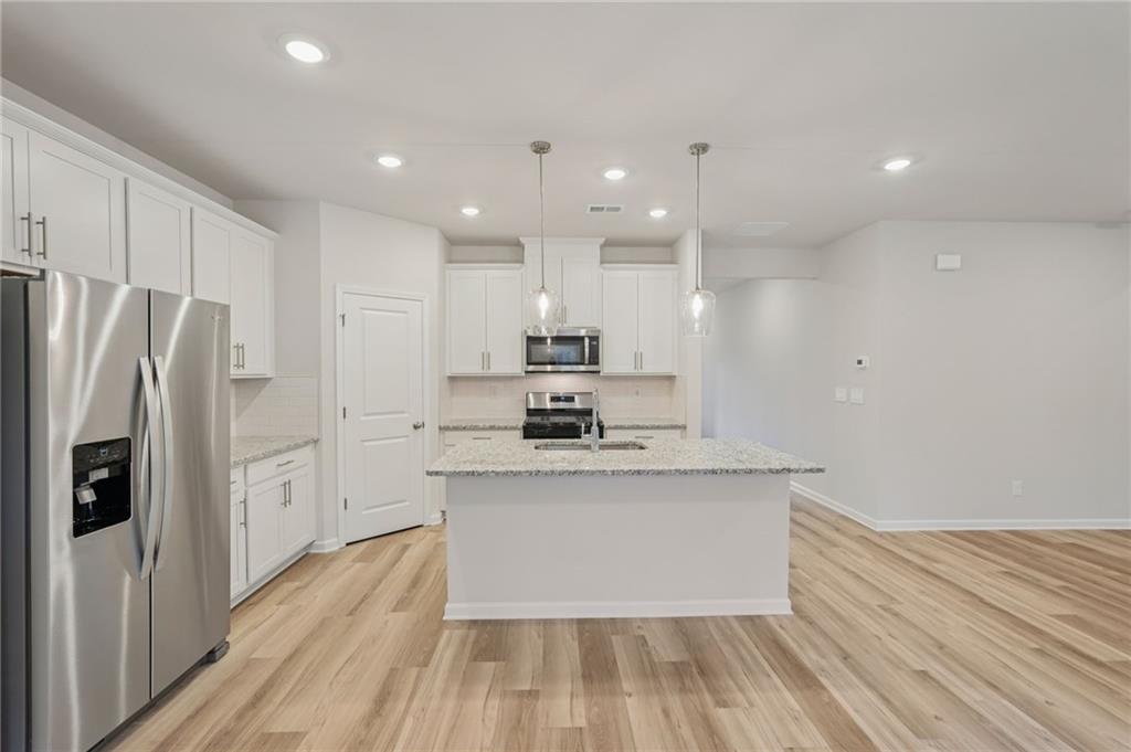 7204 Ensemble Court Fairburn, GA 30213 - Photo 15 of 56 a large kitchen with stainless steel appliances kitchen island a large counter top and wooden floors