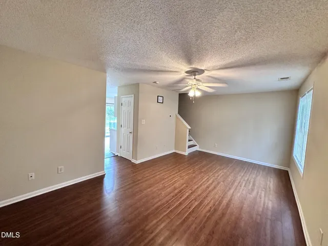 an empty room with wooden floor fan and windows