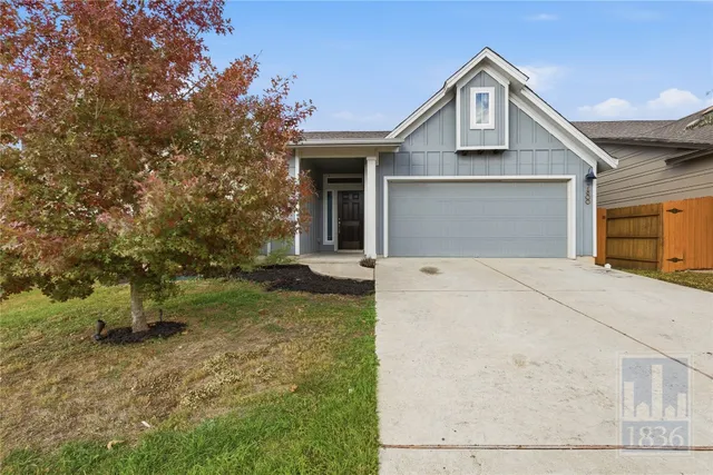 a view of a white house next to a yard with large trees