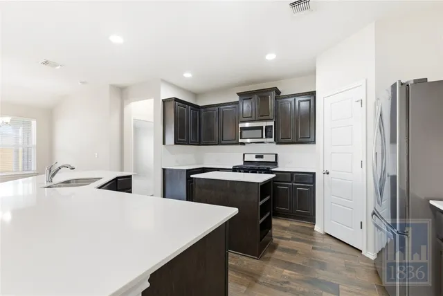 a kitchen with stainless steel appliances a sink stove refrigerator and cabinets
