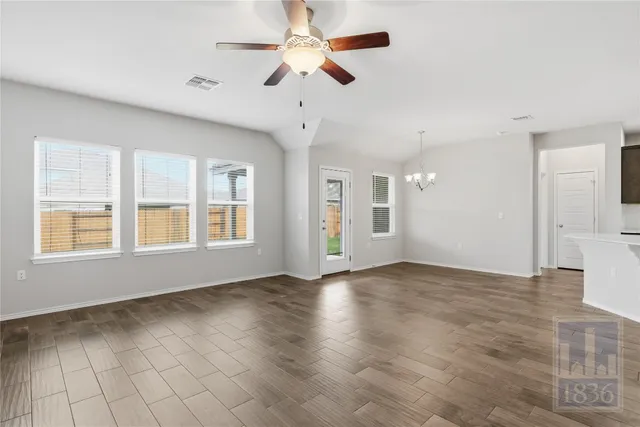 a view of an empty room with chandelier fan and fire place