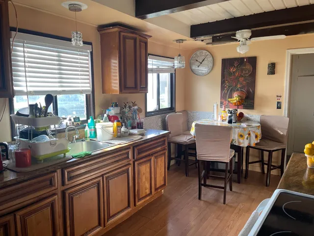 a dining hall with granite countertop a stove a sink dishwasher and a dining table with wooden floor