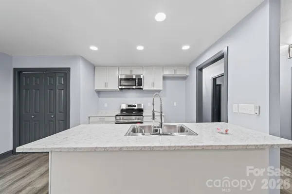 a kitchen with stainless steel appliances granite countertop white cabinets and a stove