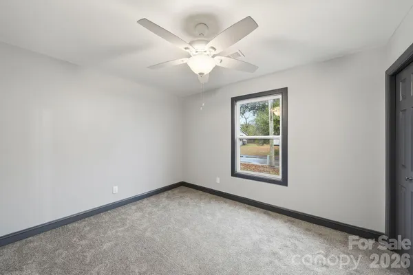 an empty room with windows and fan
