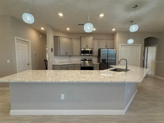 a large kitchen with kitchen island a counter top space a sink and appliances