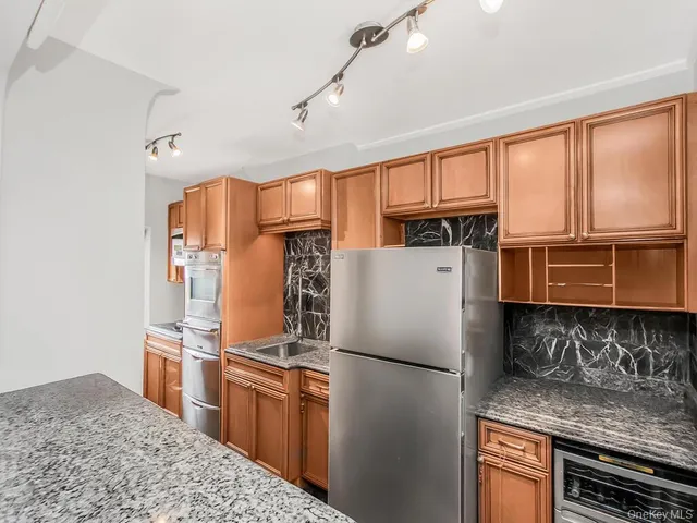 a kitchen with stainless steel appliances granite countertop a refrigerator a stove and a sink with cabinets