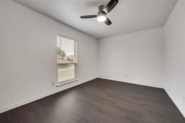 an empty room with wooden floor ceiling fan and windows