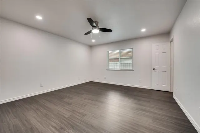 an empty room with wooden floor ceiling fan and windows