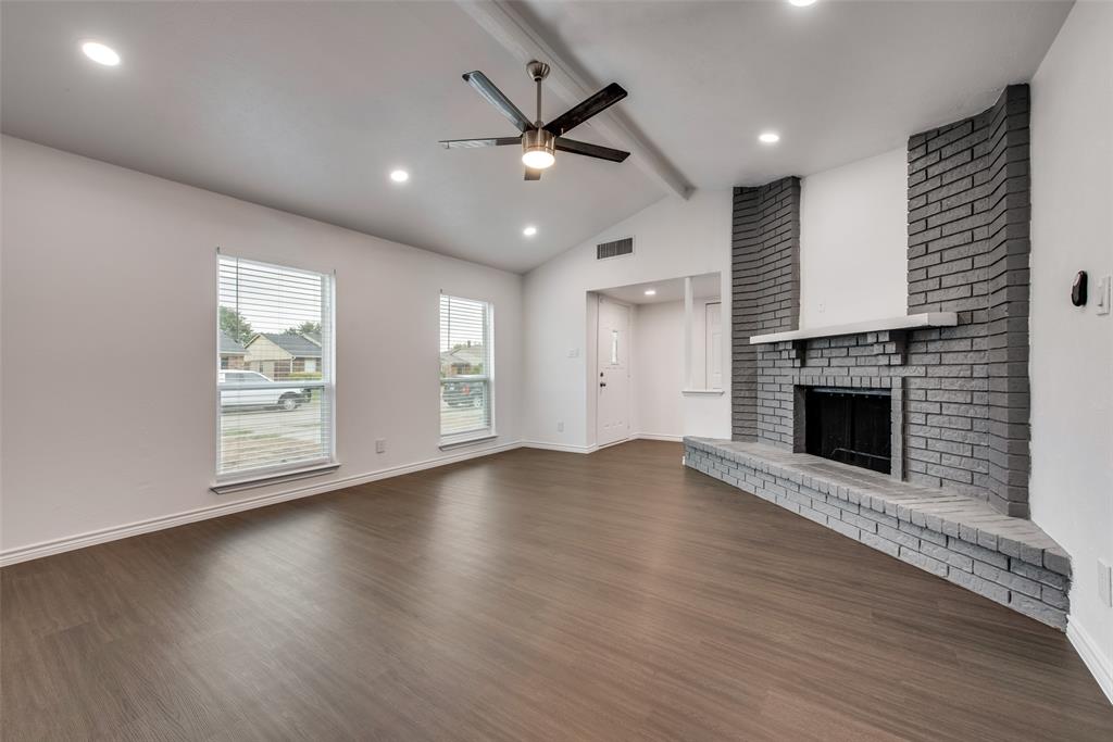 5412 Rice Drive The Colony, TX 75056 - Photo 5 of 17 an empty room with windows a fireplace a ceiling fan and wooden floor