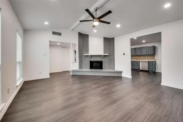 an empty room with wooden floor and a kitchen