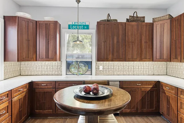 a kitchen with stainless steel appliances granite countertop a stove a refrigerator a sink dishwasher and a dining table with wooden floor