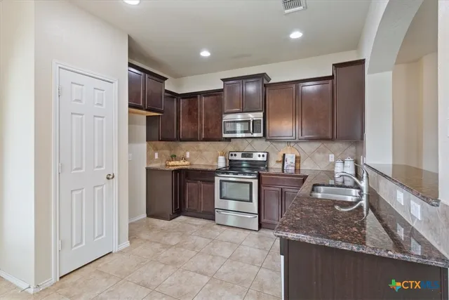 a kitchen with stainless steel appliances granite countertop a stove sink and cabinets
