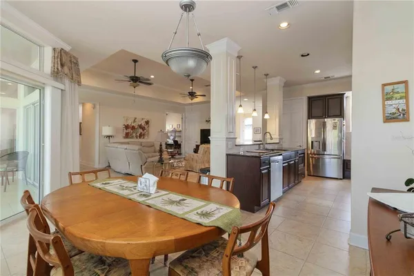 a dining room with stainless steel appliances kitchen island granite countertop a table chairs and a refrigerator