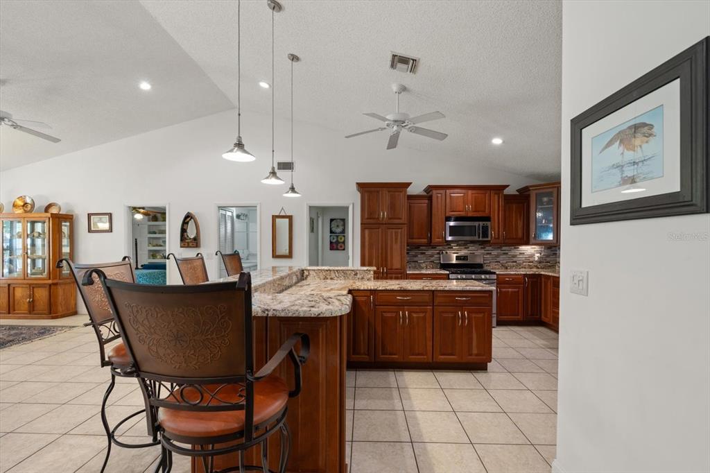 13719 Seminole Trail Wimauma, FL 33598 - Photo 11 of 68 a kitchen with stainless steel appliances granite countertop a stove a refrigerator a kitchen island a dining table and chairs