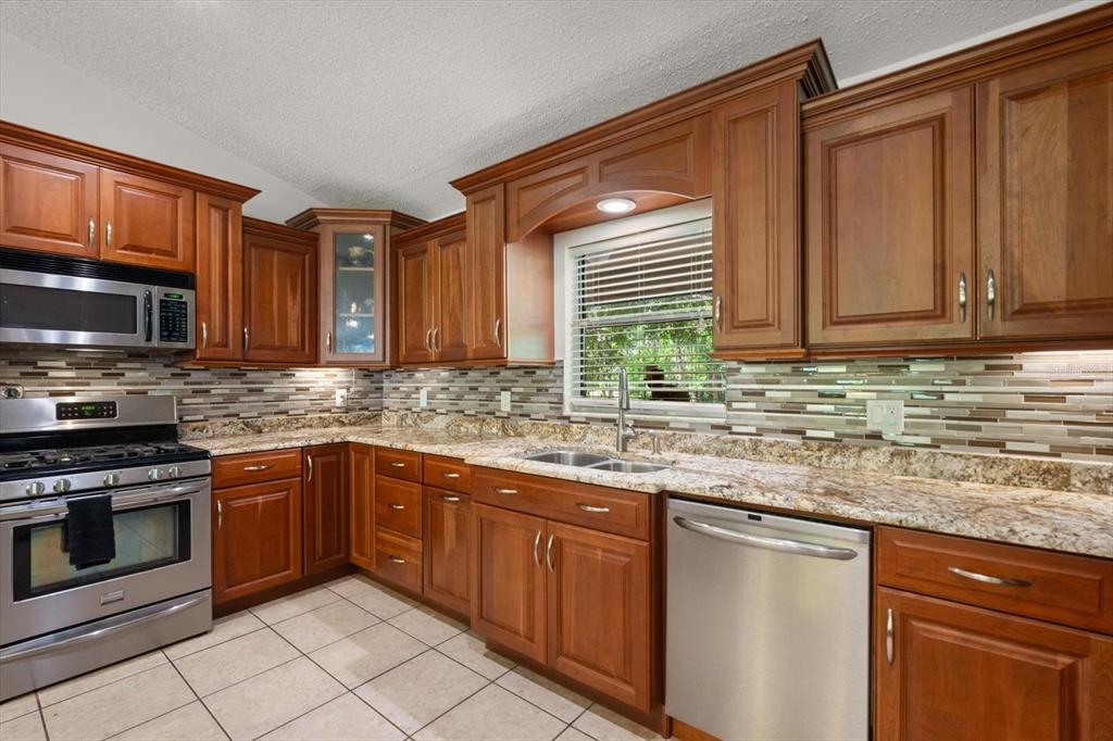 13719 Seminole Trail Wimauma, FL 33598 - Photo 13 of 68 a kitchen with stainless steel appliances granite countertop a sink stove and microwave