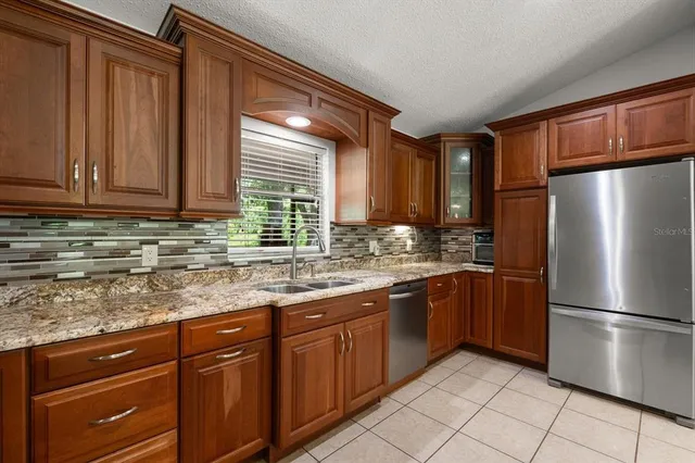 a kitchen with stainless steel appliances granite countertop a stove top oven a sink a dining table and chairs