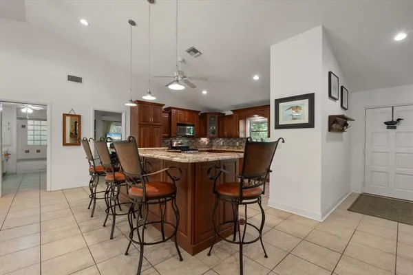 a kitchen with stainless steel appliances granite countertop a stove a refrigerator a kitchen island a dining table and chairs