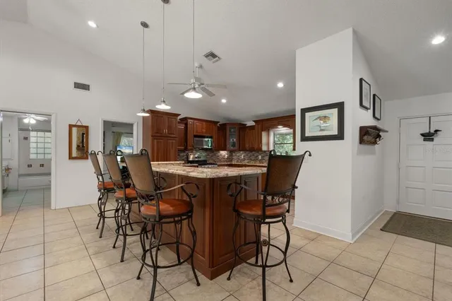 a kitchen with stainless steel appliances granite countertop a stove a refrigerator a kitchen island a dining table and chairs