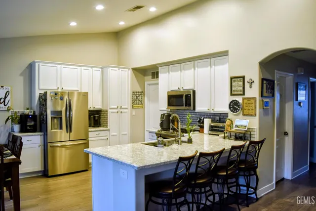 a kitchen with stainless steel appliances a dining table chairs refrigerator and sink