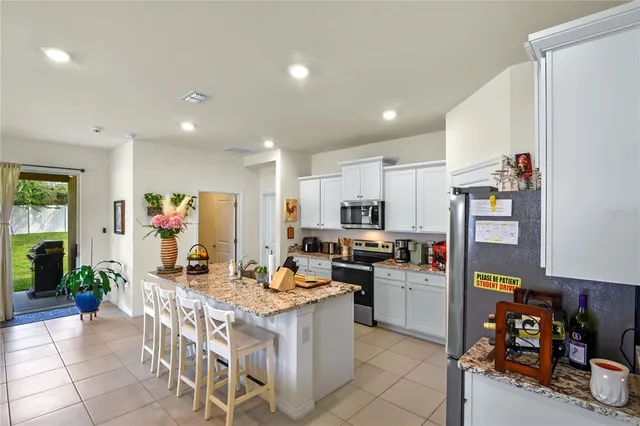 a kitchen with stainless steel appliances kitchen island granite countertop a stove refrigerator and cabinets