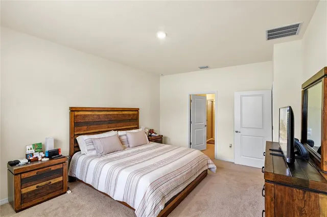 a bedroom with a bed and a flat tv screen on a dresser