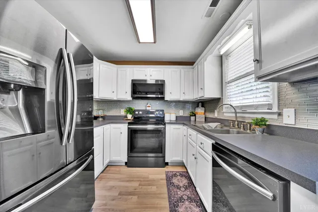 a kitchen with stainless steel appliances granite countertop a refrigerator a sink a stove a microwave and wooden cabinets