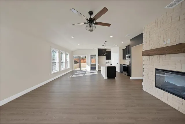 a view of an empty room with a kitchen and a fireplace