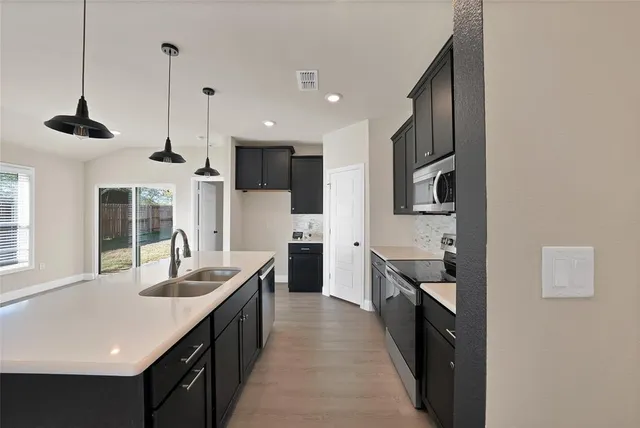 a kitchen with stainless steel appliances kitchen island a sink and a wooden floor