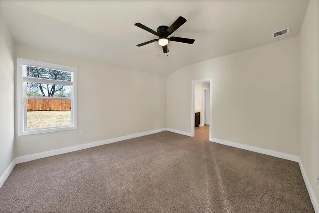 an empty room with ceiling fan and windows